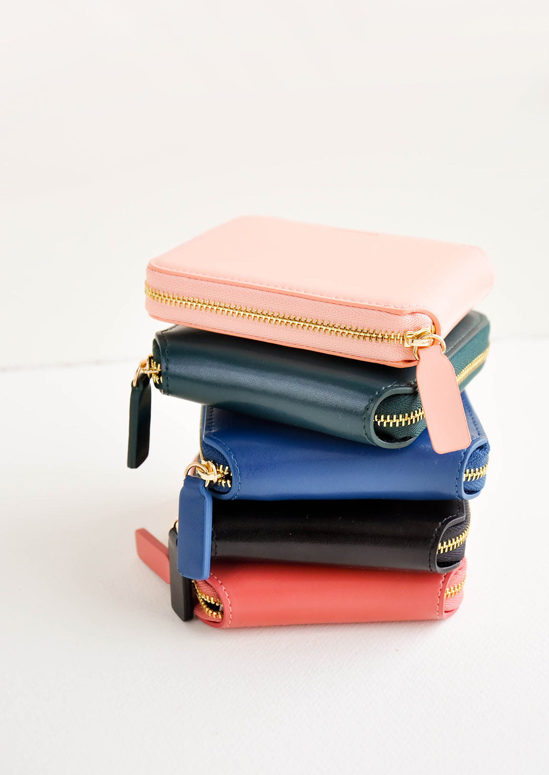 Product show showing multiple colors of zip wallet in a stack.