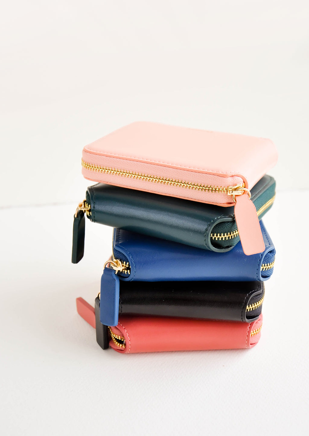 9: Product show showing multiple colors of zip wallet in a stack.