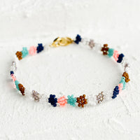 Navy Multi: A beaded bracelet in flower shape in neon peach, turquoise, white and navy.