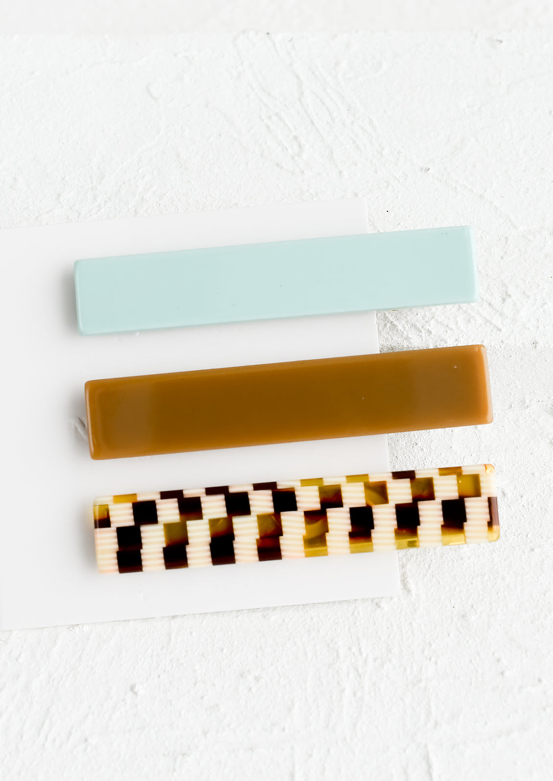 A set of three rectangular acetate hair clips in aqua and brown mix.