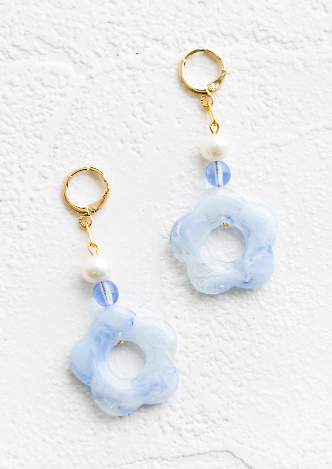 A pair of pearl and blue/white flower beaded dangle earrings strung from a gold huggie hoop.