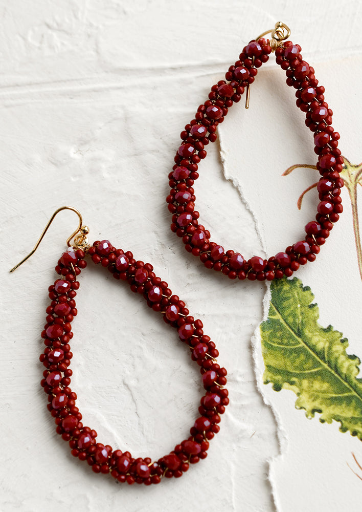 A pair of teardrop shape earrings with burgundy floral beading.