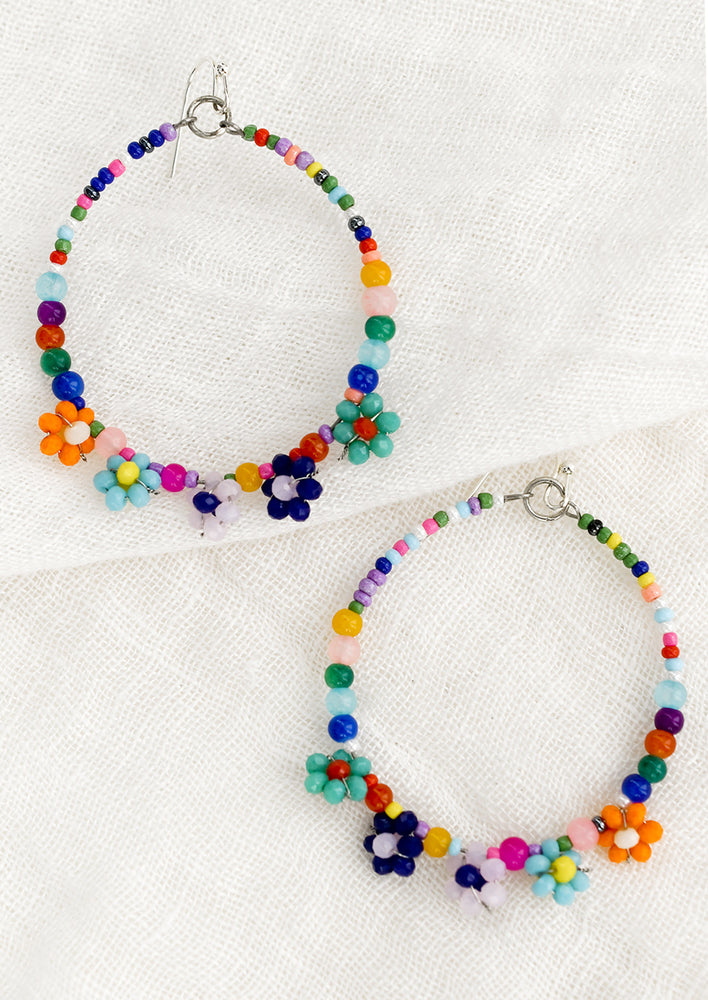 A pair of multicolor beaded hoop earrings with flower beading.