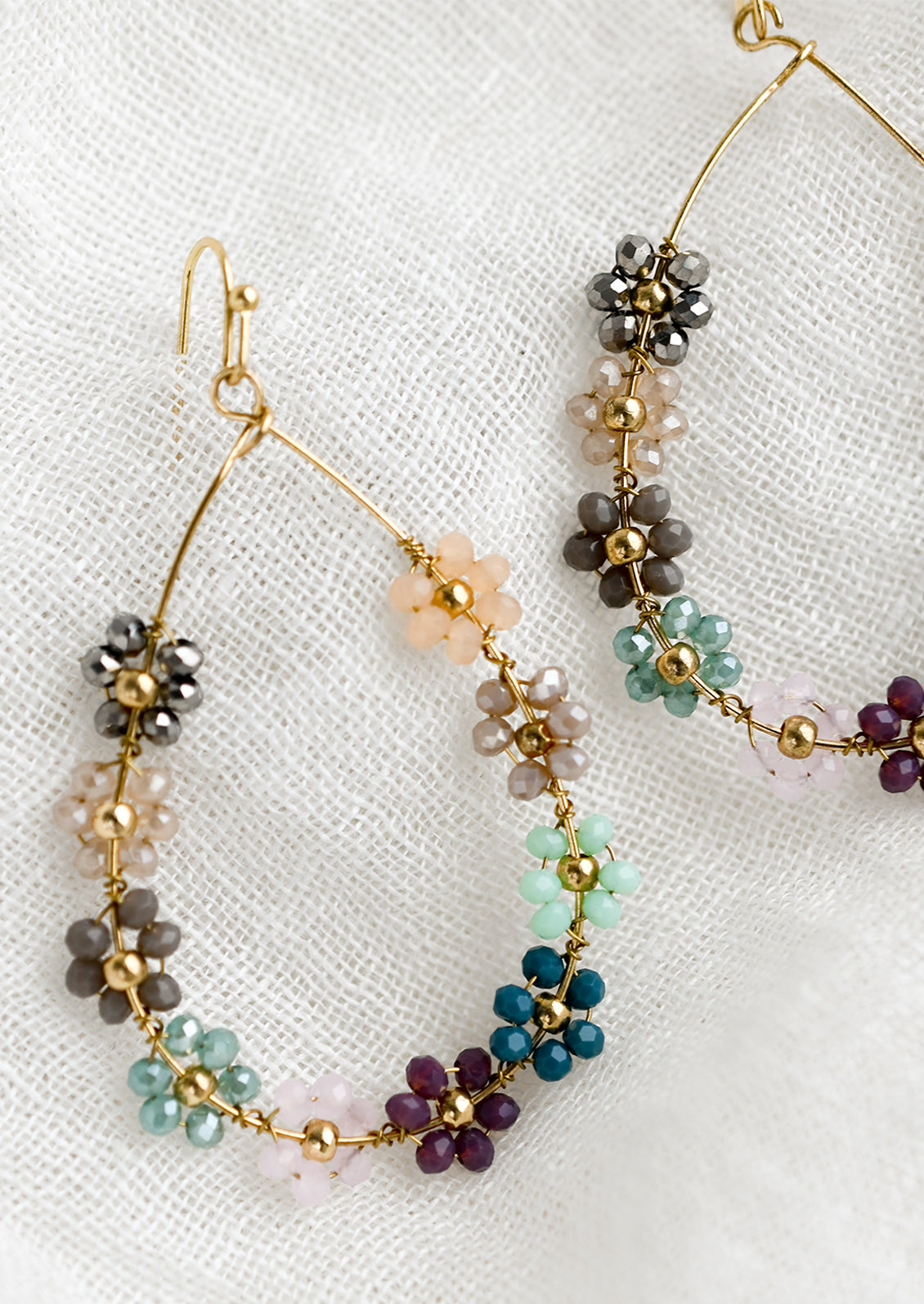 A pair of gold teardrop wire earrings with cool hued floral beading.