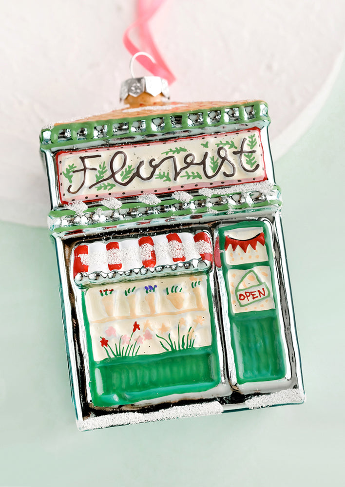 1: A glass holiday ornament in shape of florist shop building.
