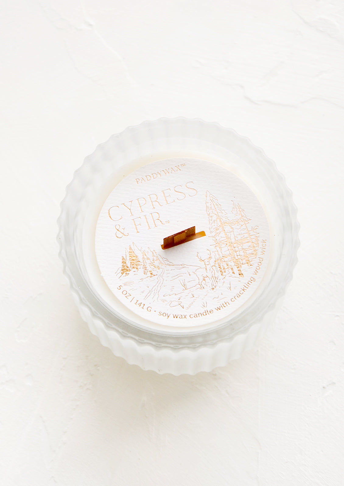 Scented candle in a frosted, fluted glass vessel.