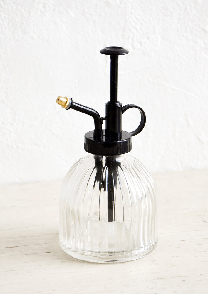 A plant mister bottle with fluted glass base and black pump.