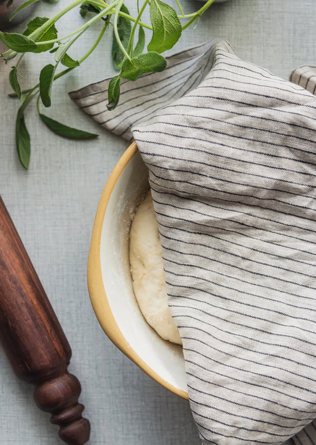 Natural / Black Pinstripe: A linen tea towel in tan and black pinstripe covering a bowl of rising dough.