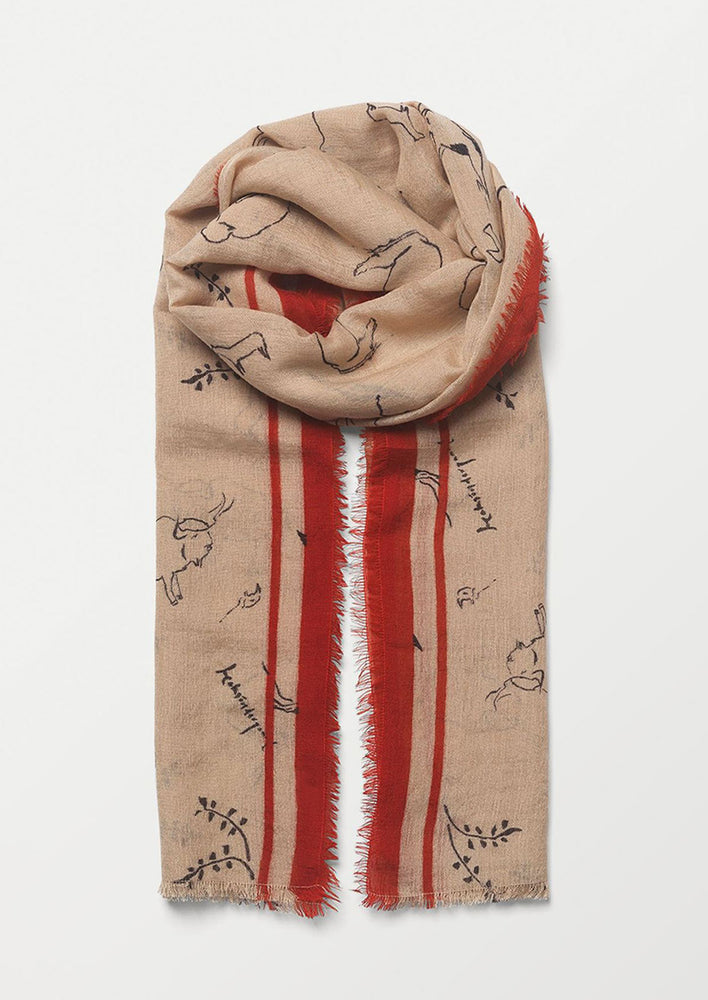 A nude colored scarf with red trim and sketched pattern.
