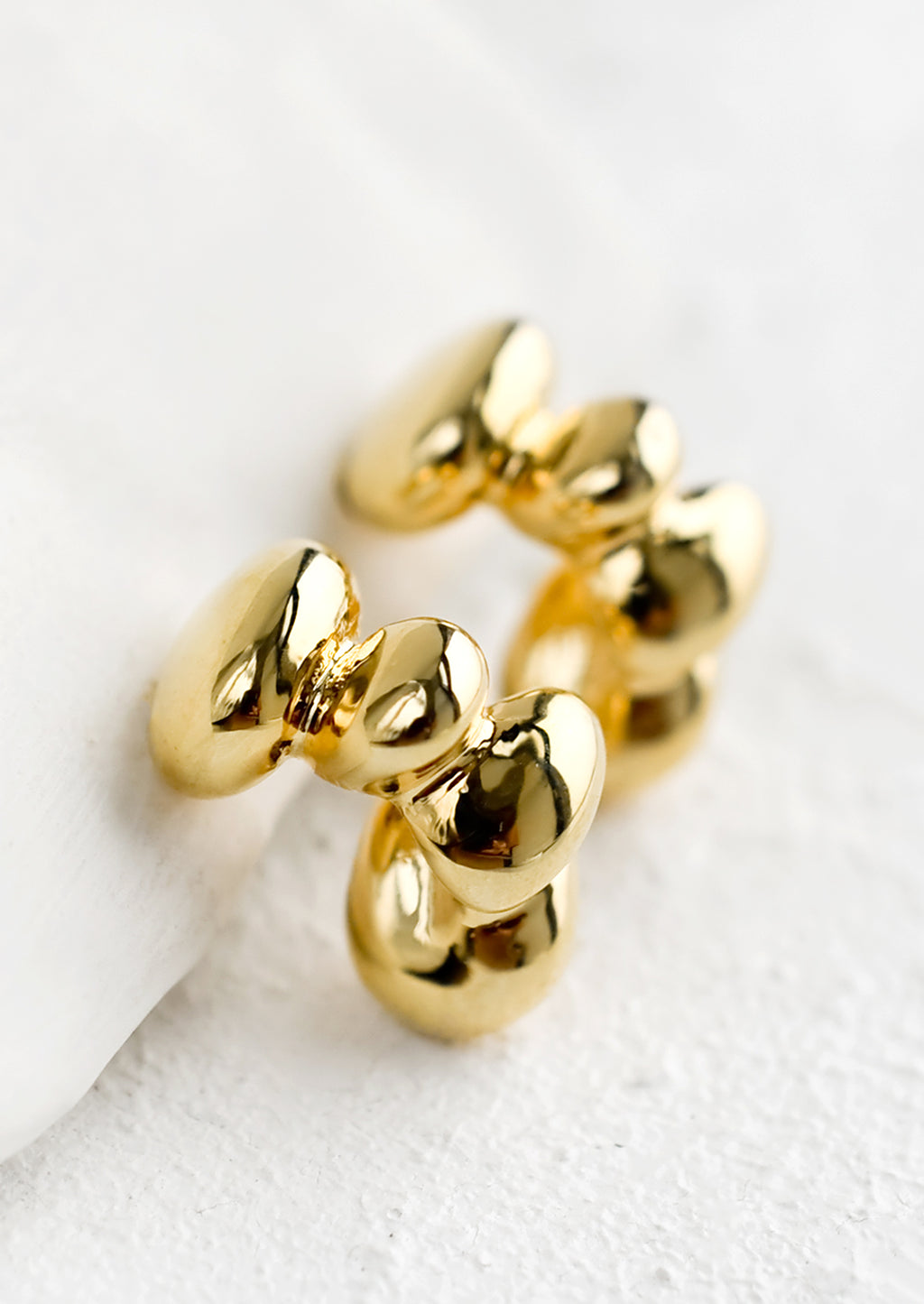 Gold: A pair of gold hoop earrings in melty blob shape.