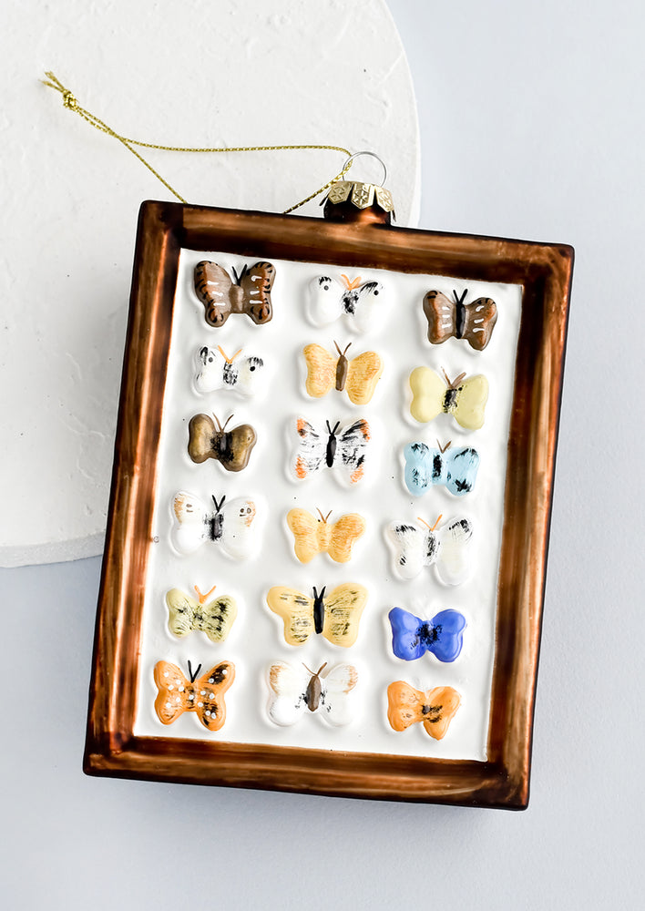 A decorative glass ornament in frame shape with butterflies.