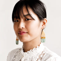 3: Model shot of woman wearing beaded earrings and white top.