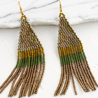Fern Multi: Beaded earrings featuring olive, ochre and brown beads layered into fringe, dangling from a gold hoop.