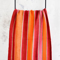 2: Colorful, striped woven textile intended for use as a rug or blanket, hung on a display ladder.