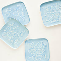 Aqua: Square coasters in blue enamel with raised floral motif