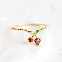 Cherry / Size 5: A gold ring with beaded texture and cherry shaped crystal front.