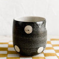 Black: A black ceramic cup with white polka dots.