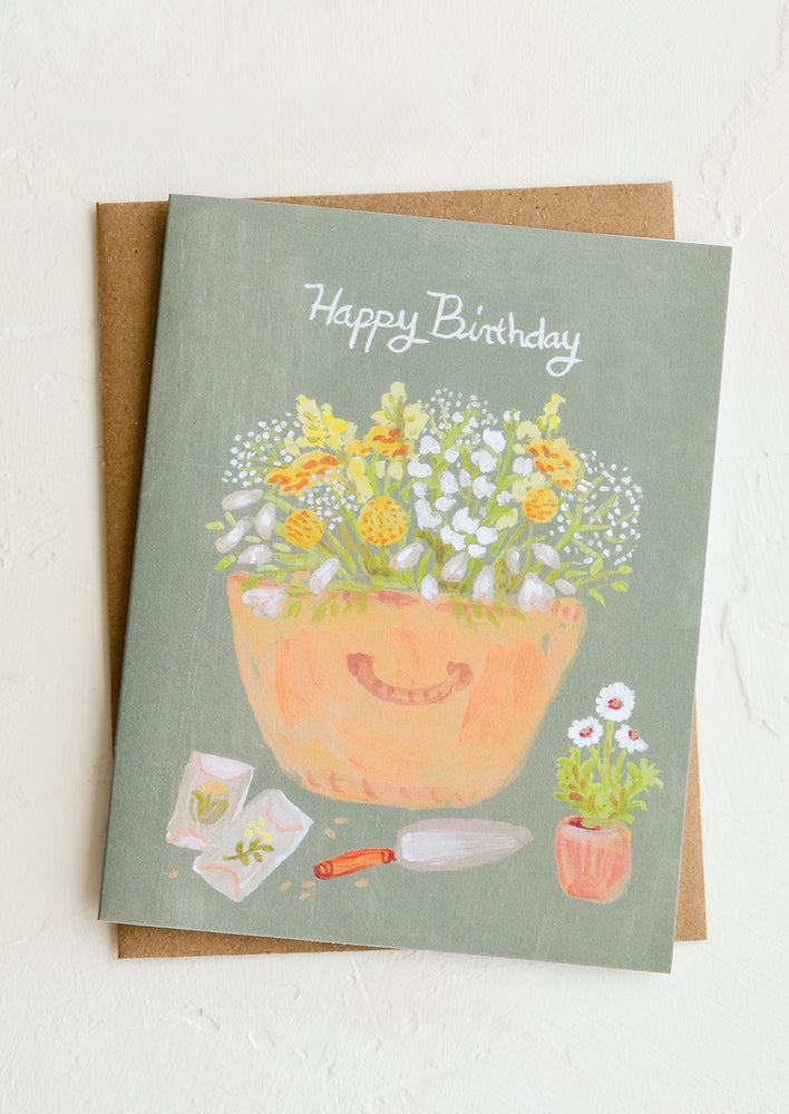 1: A birthday card with sage green background and illustration of gardener's basket.
