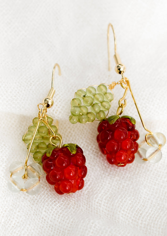 A pair of earrings with glass raspberry, and green beaded leaves.