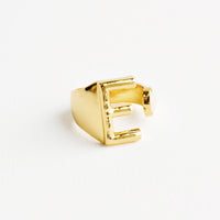 E: Yellow gold ring with letter E and oval glass crystal, and wide adjustable band.