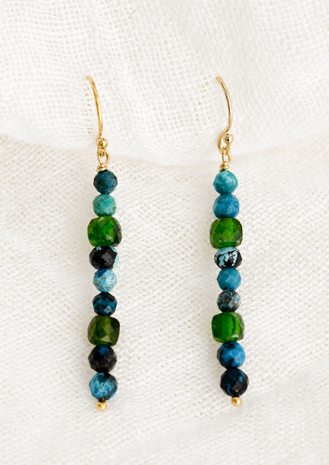 A pair of turquoise and green beaded mixed gemstone earrings in a straight line.