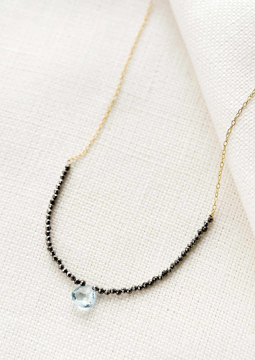 Pyrite / Blue Topaz: A beaded necklace with small pyrite beads and blue topaz teardrop.