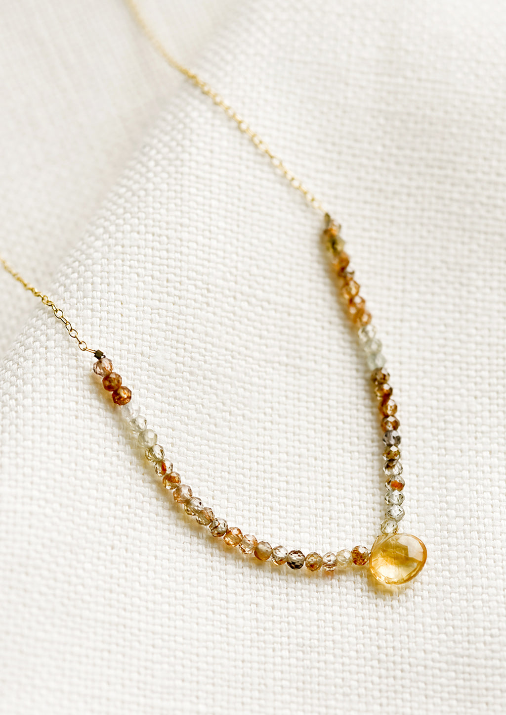 Citrine / Quartz: A beaded necklace with small gemstone beads and citrine teardrop.
