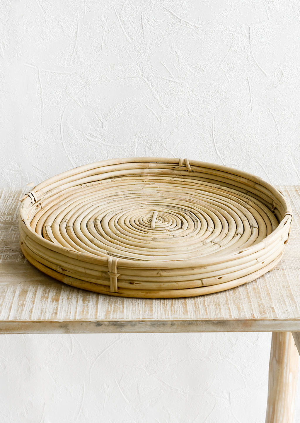 2: A round, shallow woven tray made from rattan.