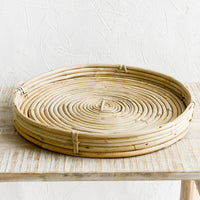 2: A round, shallow woven tray made from rattan.