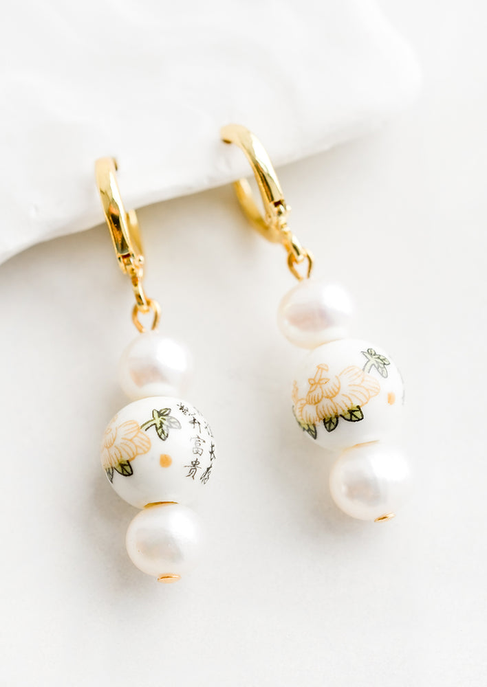 A pair of pearl earrings with gold huggie hoop clasp and Chinese ceramic beads.