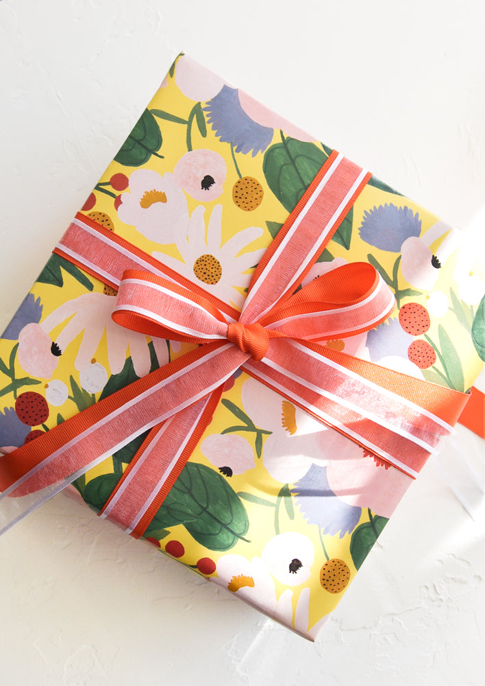 A gift wrapped box with floral wrapping paper and a red and white bow