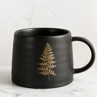 1: A black ceramic mug with single gold fern print.