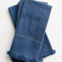 1: A set of four blue napkins with fine gold stitching.