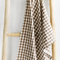 Cocoa: A gingham print tea towel in brown and white.