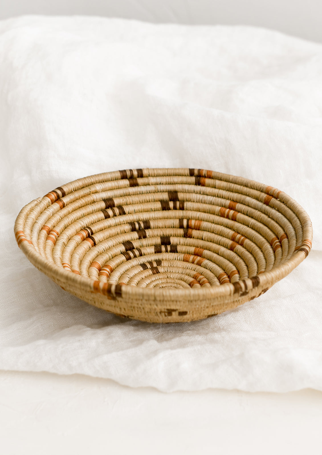 A tan woven bowl with brown and terracotta accents.