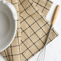 Sepia Check: A sepia toned tea towel with black grid pattern folded under a bowl with a whisk