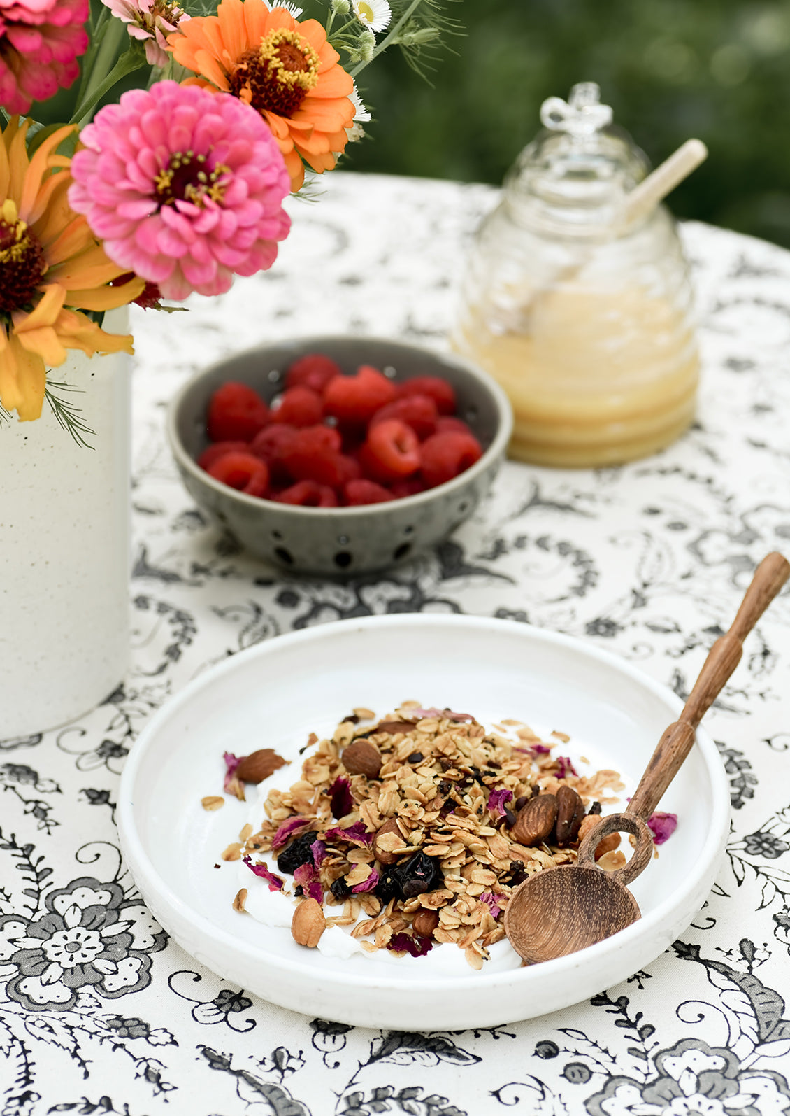 A ceramic bowl with yogurt and granola and wooden spoon.