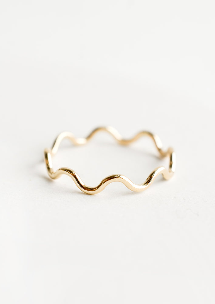 A gold stacking ring in curvy ripple shape.