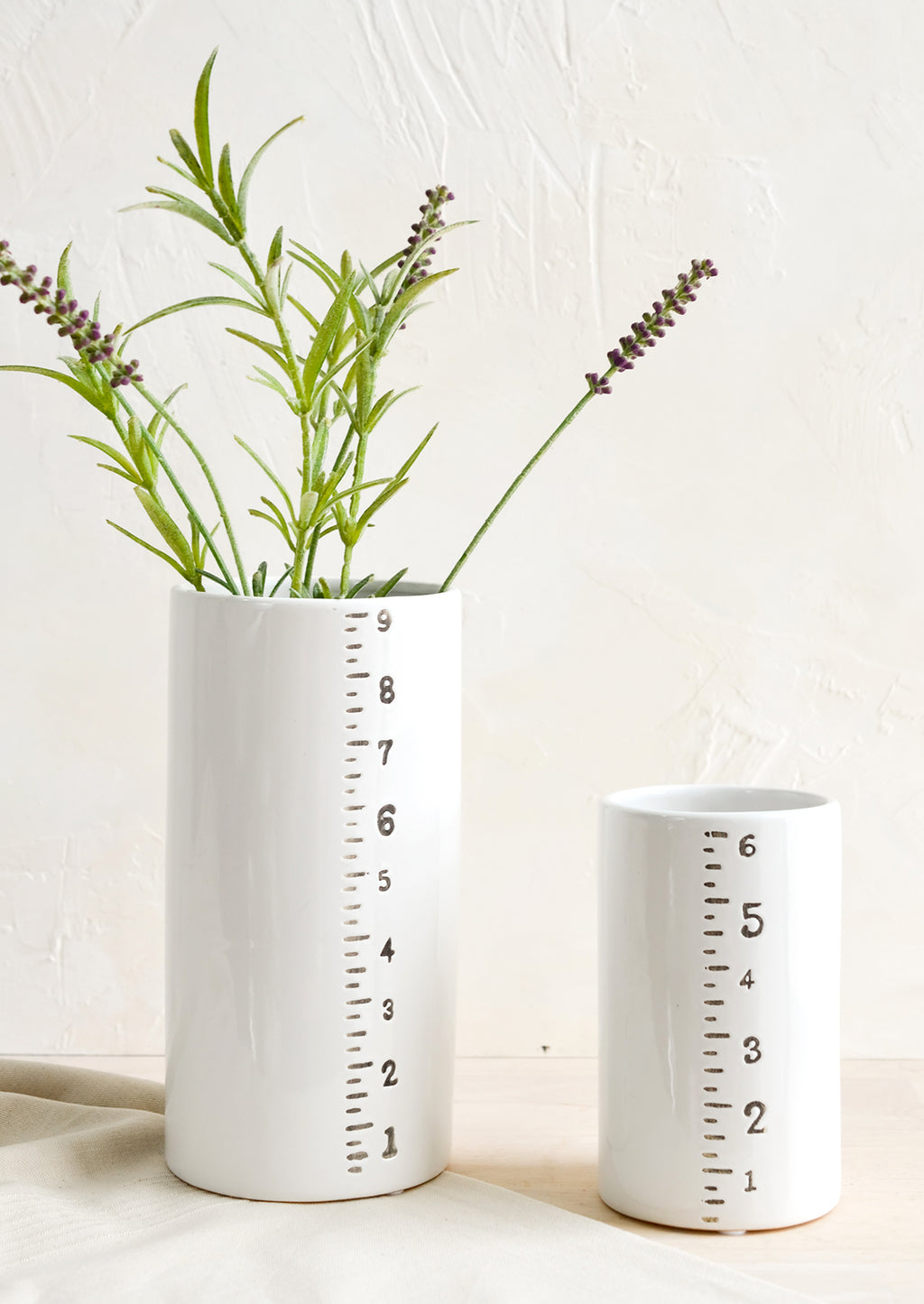 1: Short and tall ceramic vases with ruler detailing on side.
