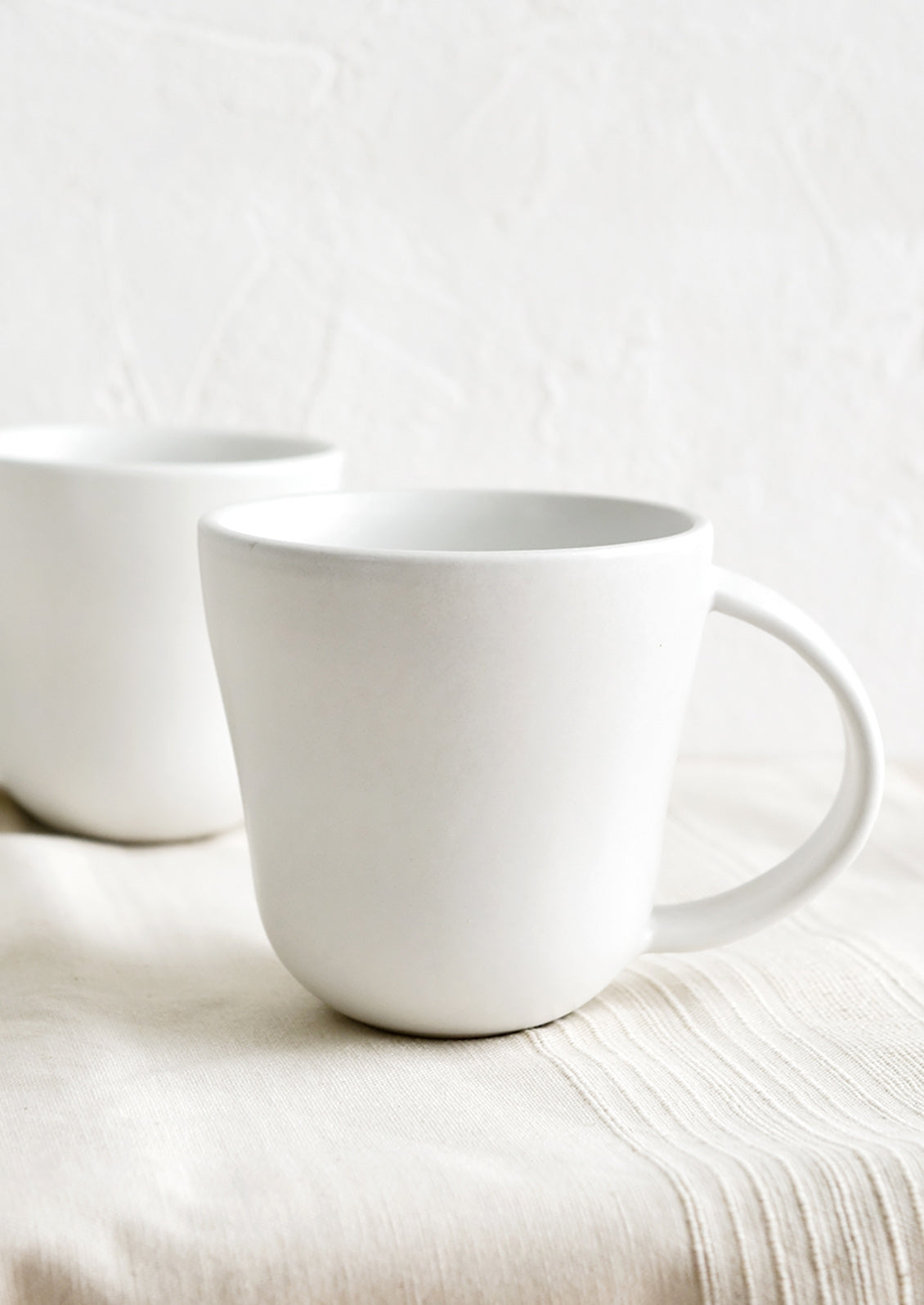 A matte white ceramic mug with softly curved shape.