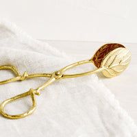 1: A pair of brass scissor-style serving tongs in leaf design.