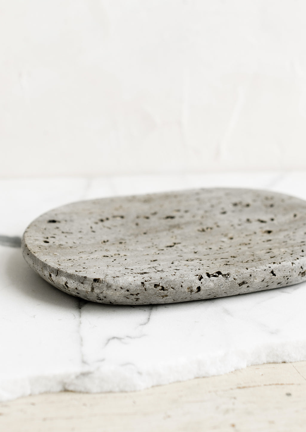 2: An oval-shaped soap dish in grey travertine.