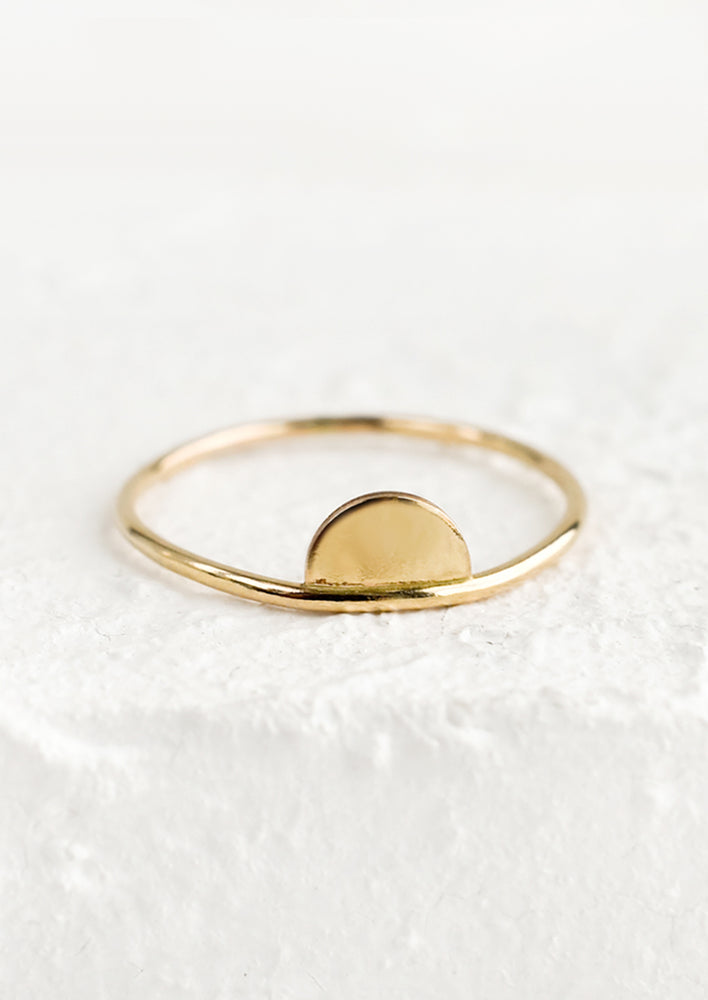 A thin gold stacking ring with half moon shape on top.
