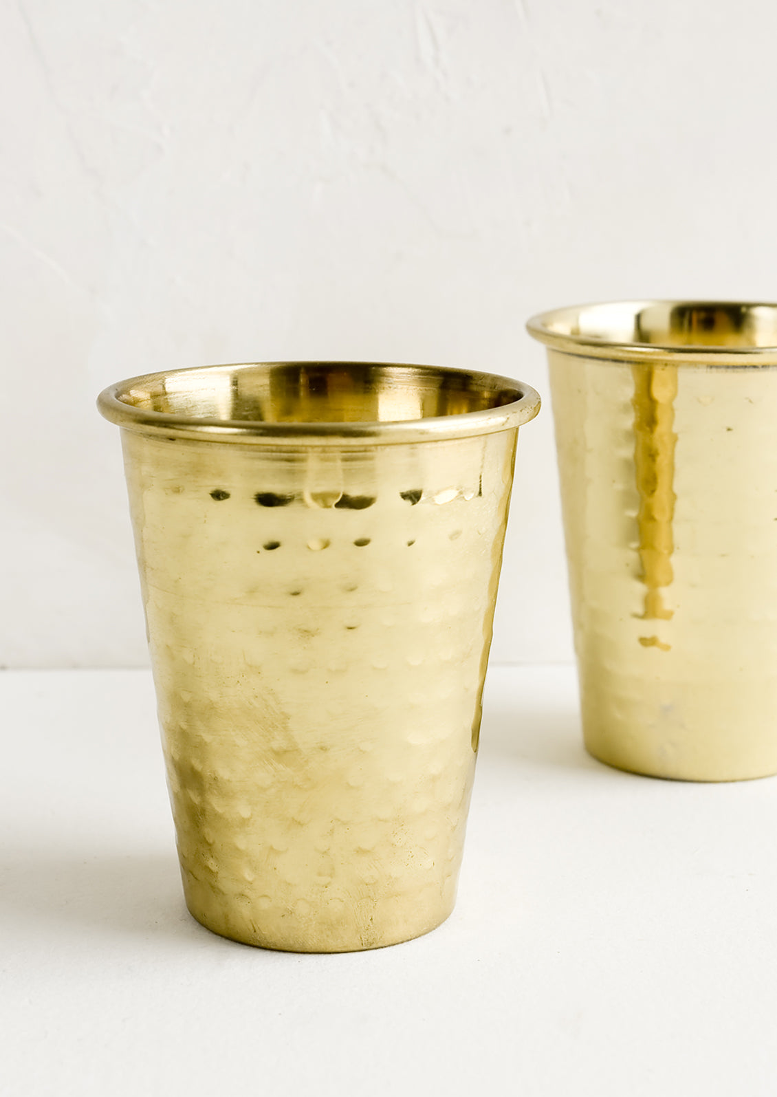 Two hammered brass tumblers.