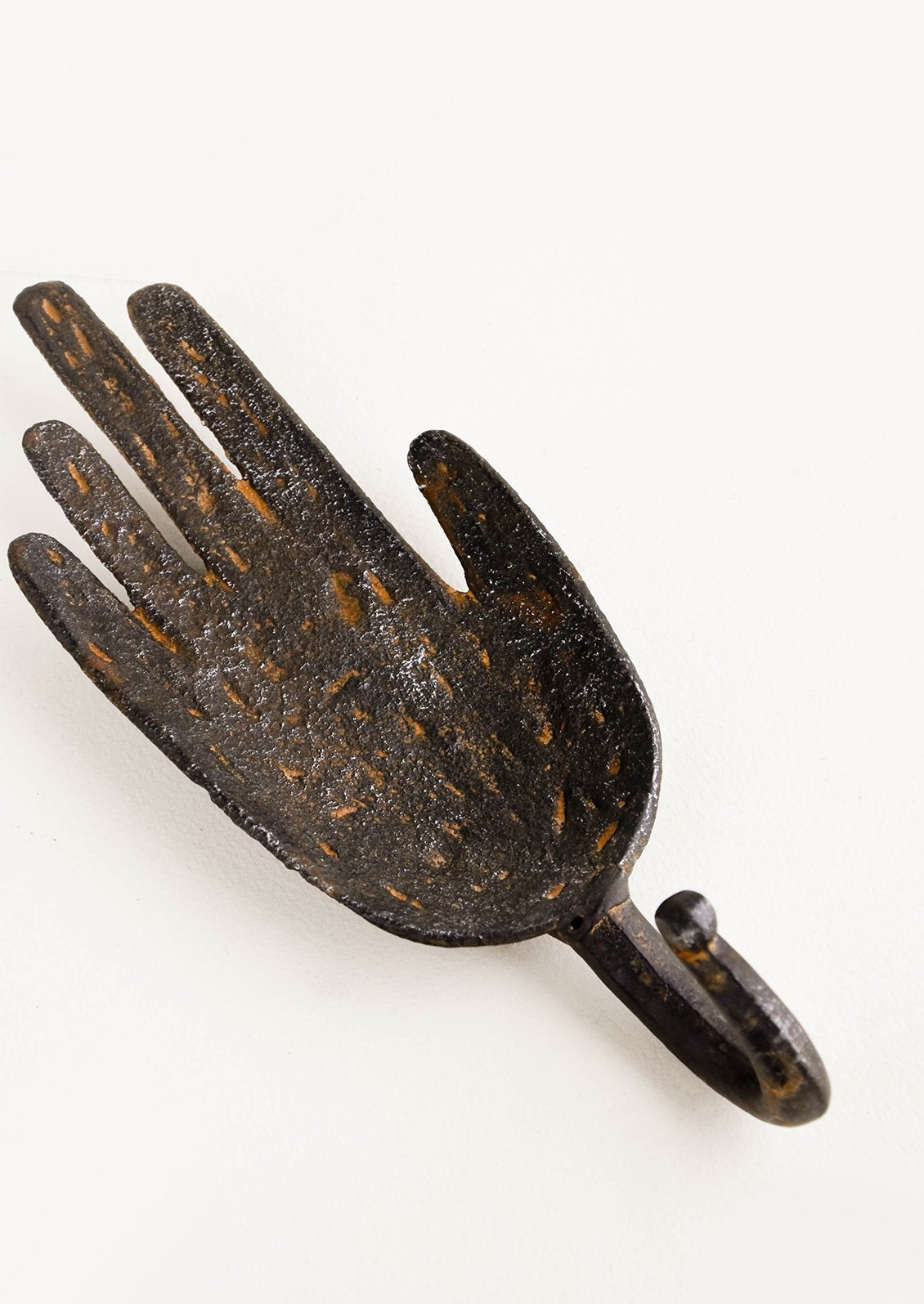 Wall hook in the shape of a hand with hook below, made in dark distressed metal