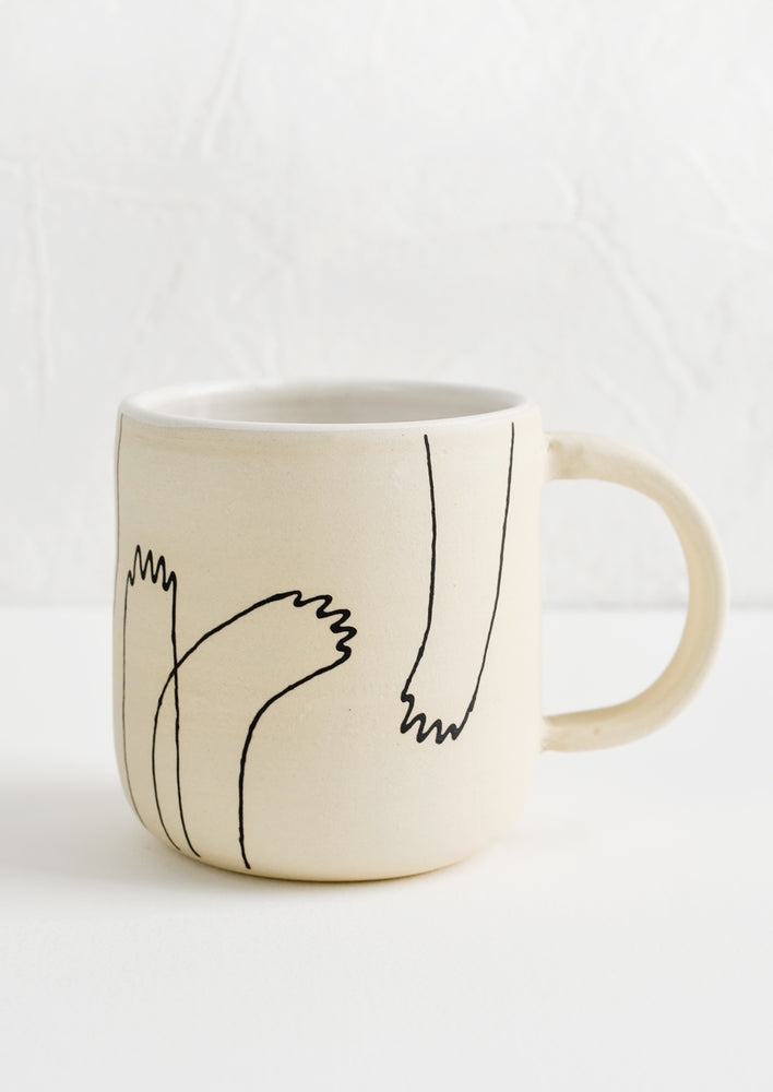 1: An ivory clay ceramic mug with hand drawn imagery of creature-like hands.