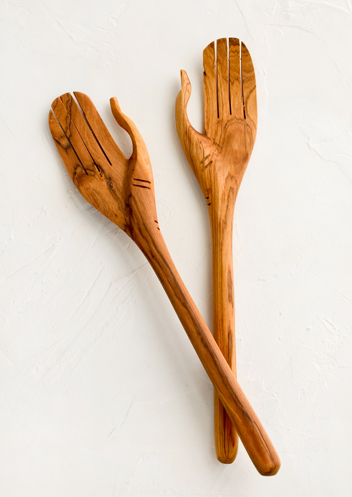 A pair of wooden salad servers carved in the shape of a pair of hands.