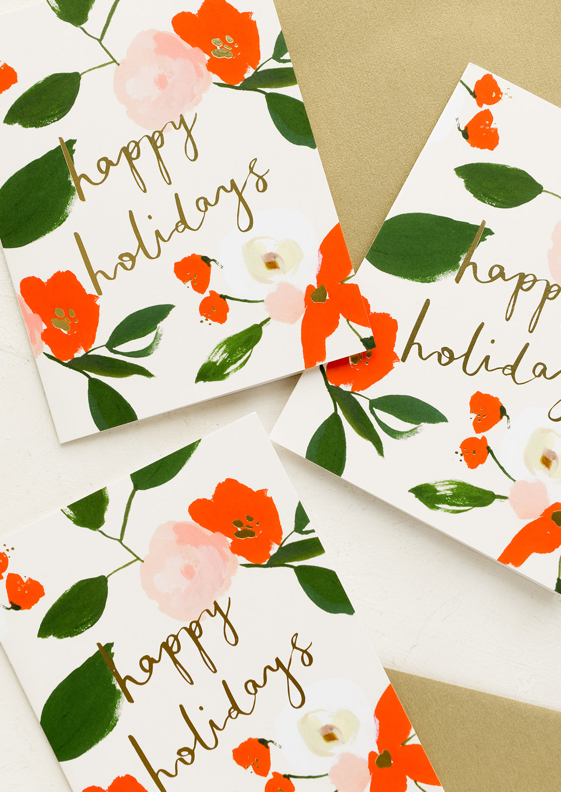 Red and green floral print greeting cards with "Happy holidays" in gold script.