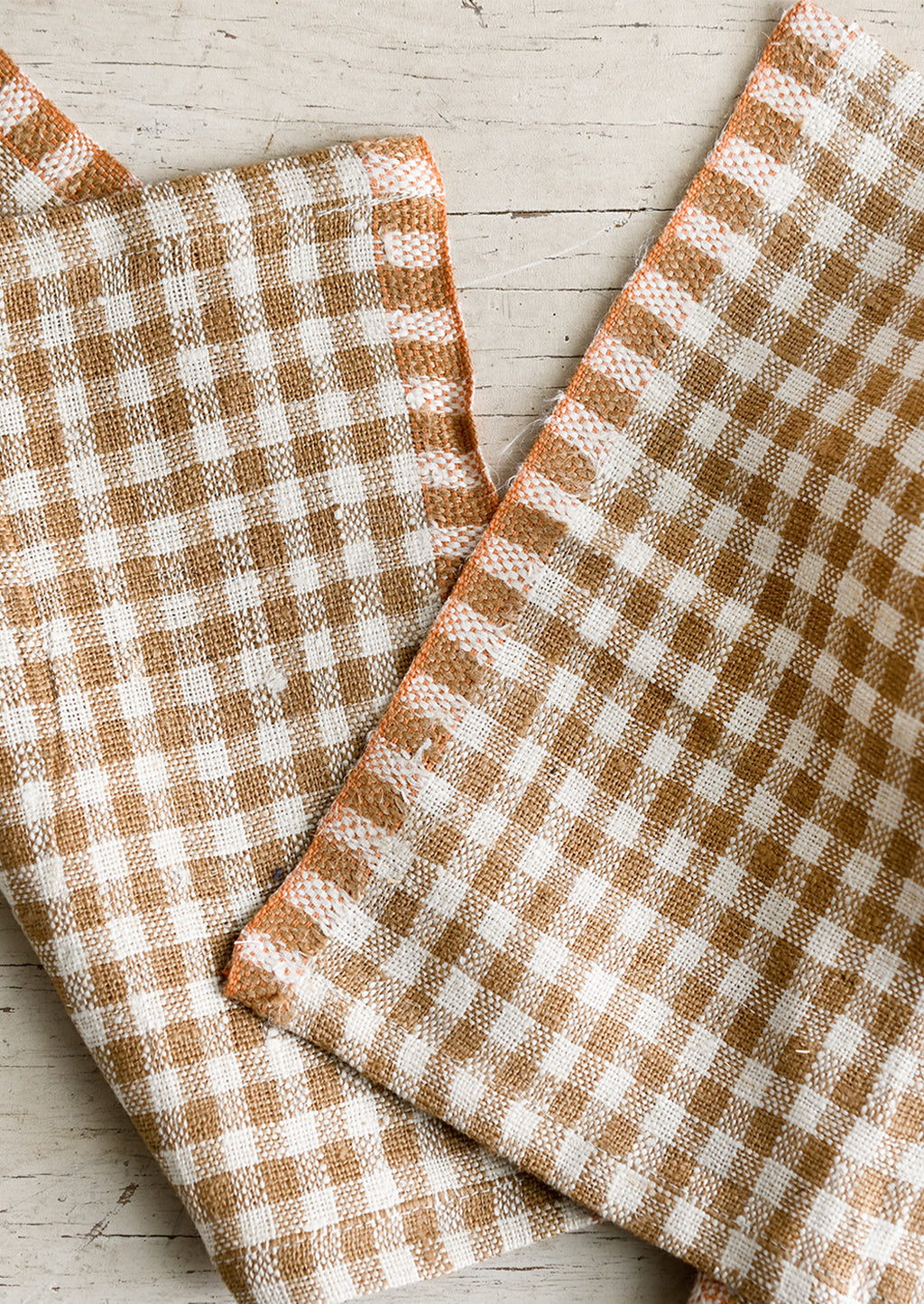 Coffee: A pair of coffee brown gingham cocktail napkins with orange trim.