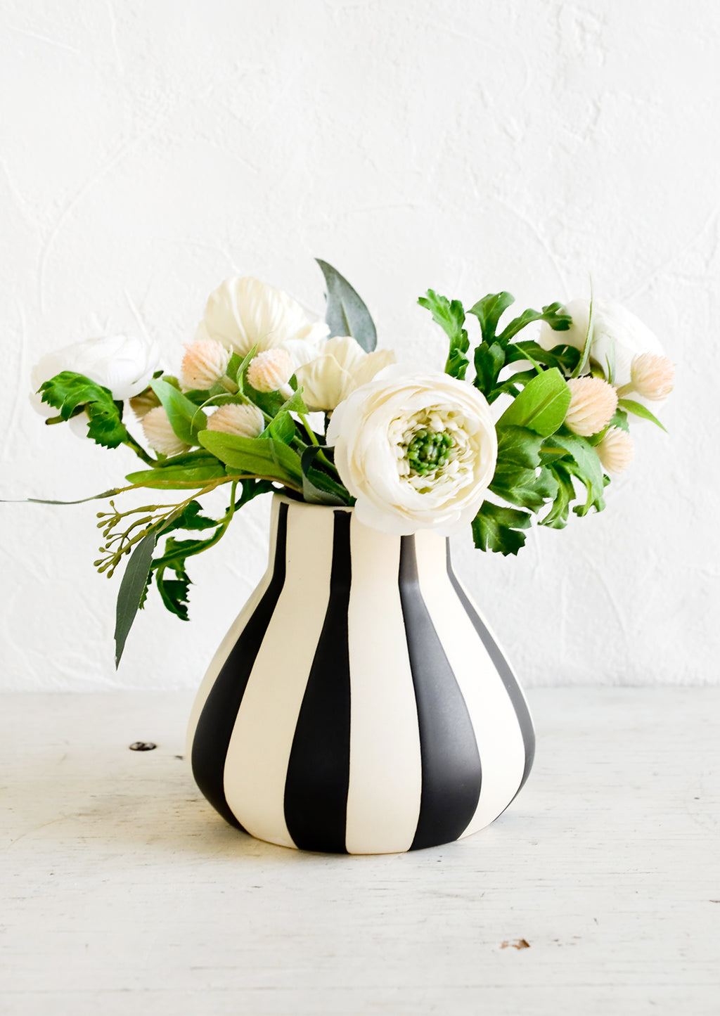 Wide Stripes: A flower arrangement in a white ceramic vase with thick black stripes.